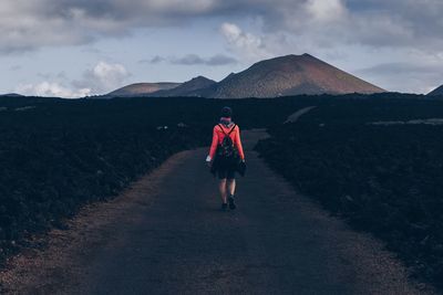 Rear view of woman standing on mountain against sky