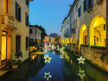 Canal amidst buildings in city against sky