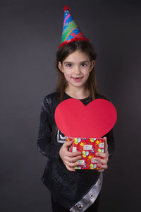 Portrait of smiling girl holding heart shape