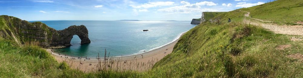 Panoramic shot of durdle door and sea against sky