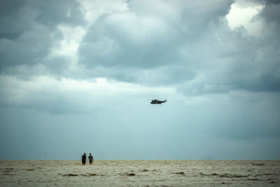 Helicopter flying over sea against sky