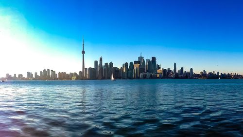 City at waterfront against blue sky