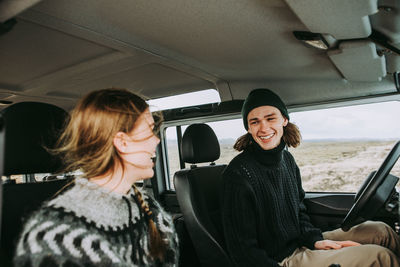 Smiling man and woman talking while sitting in car