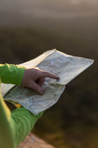 Close up of senior male hands holding a map on top of mountain during sunset