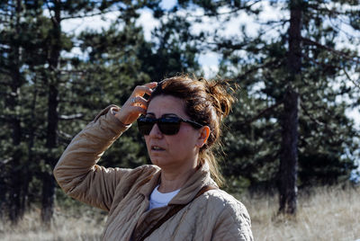 Mature woman with hand in hair standing on field