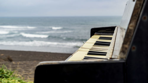 Close-up of piano at beach against sky