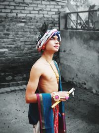 Boy wearing costume standing against wall outdoors