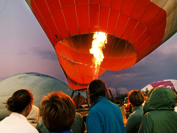 Rear view of people watching hot air balloon against sky