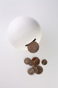 High angle view of piggy bank with coins over white background