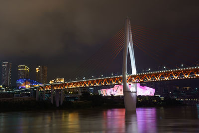 Illuminated bridge over river at night