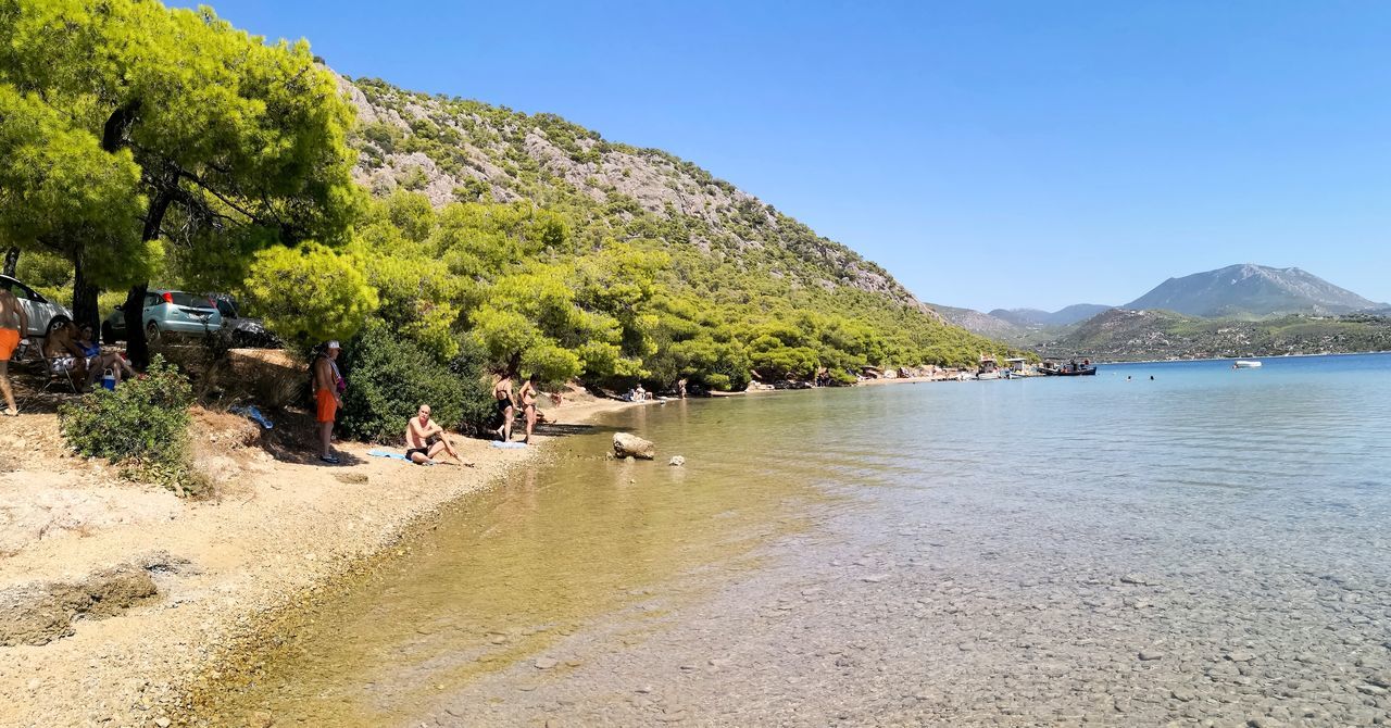 mountain, water, sky, tree, plant, nature, day, beauty in nature, beach, scenics - nature, real people, land, sunlight, incidental people, clear sky, group of people, sea, men, lifestyles, outdoors