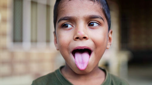 Close-up of boy sticking out tongue outdoors