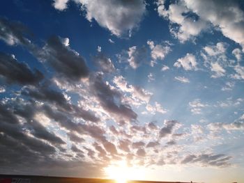 Low angle view of sunlight streaming through clouds