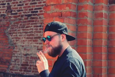 Man smoking cigarette against brick wall