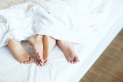 Low section of woman sitting on bed at home