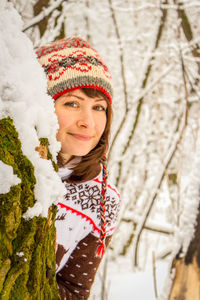 Portrait of smiling young woman standing by christmas tree during winter. beautiful girl in winter.