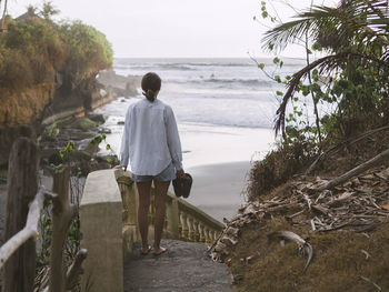 Rear view of woman walking down steps at beach