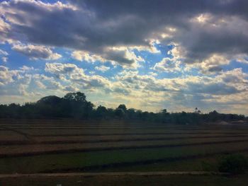 Scenic view of field against cloudy sky