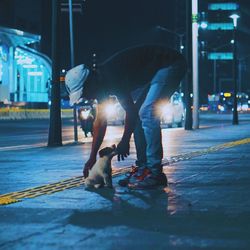 Man with umbrella on illuminated street at night