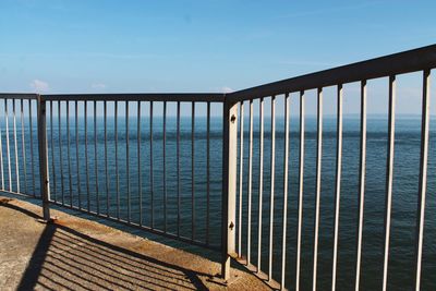 Metal railing by sea against sky