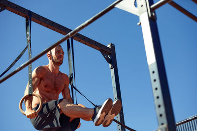 Low angle view of boy climbing against sky