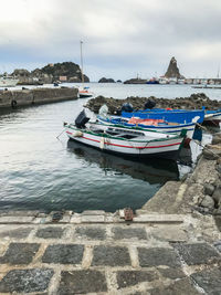 Boats moored at harbor against sky