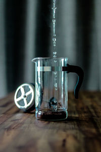 Close-up of water pouring in coffee maker on table