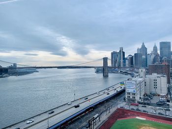 Bridge over river by buildings in city against sky