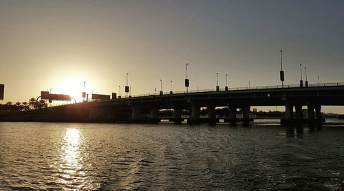 Bridge over river against sky during sunset