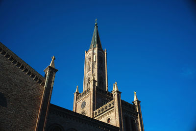 Low angle view of church spire against blue sky