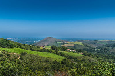 Scenic view of landscape and sea against blue sky