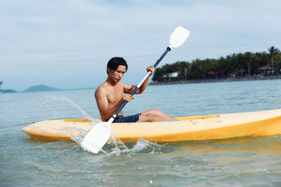 Man kayaking in sea against sky