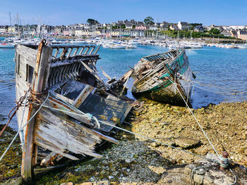 Fishing boats moored on sea shore against sky