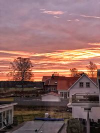 Houses and buildings against sky during sunset