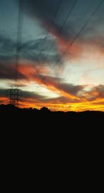 Silhouette landscape against dramatic sky during sunset