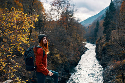 Young woman standing on road amidst trees during autumn