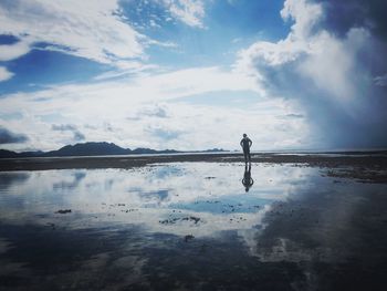 Mid distance of man standing at beach against sky