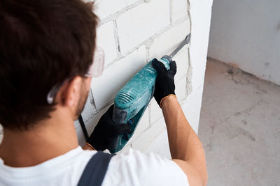 Renovation concept. man with demolition hammer remove stucco from wall