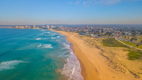 Aerial view of city by sea against sky
