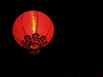 Low angle view of illuminated lantern hanging against black background