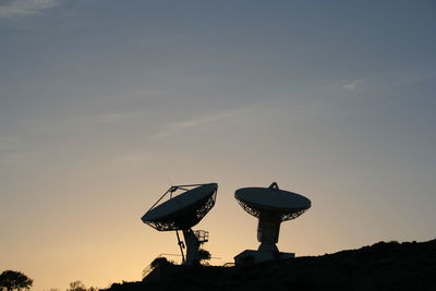 Silhouette of communications tower against sky during sunset