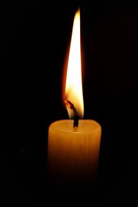 Close-up of lit candle in darkroom