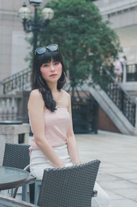 Portrait of young woman sitting at sidewalk cafe