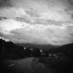 Country road against cloudy sky