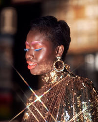 Side view of young woman looking away wearing glittery clothing