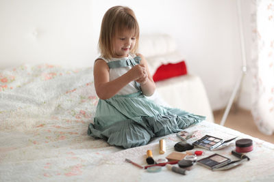 Kid girl in my mother's bedroom took out mother's make-up and lipstick, the concept of a  childhood 