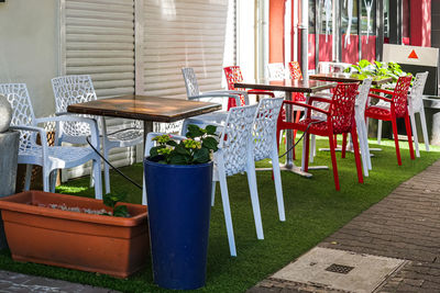 Empty chairs and table by potted plants on window