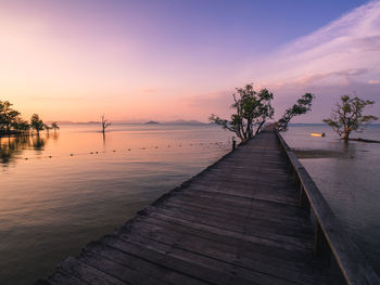 Scenic view of wooden pier bridge over peaceful sea in sunset orange sky. koh mak island, thailand.