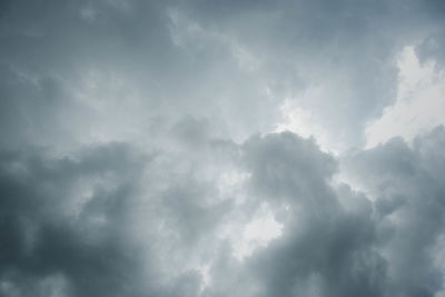 Low angle view of sunlight streaming through clouds