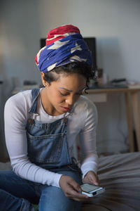 A young woman playing with a smart phone on a bed